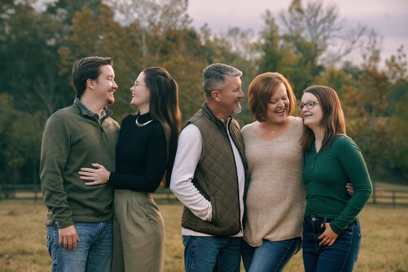 Family group smiling together in an open field