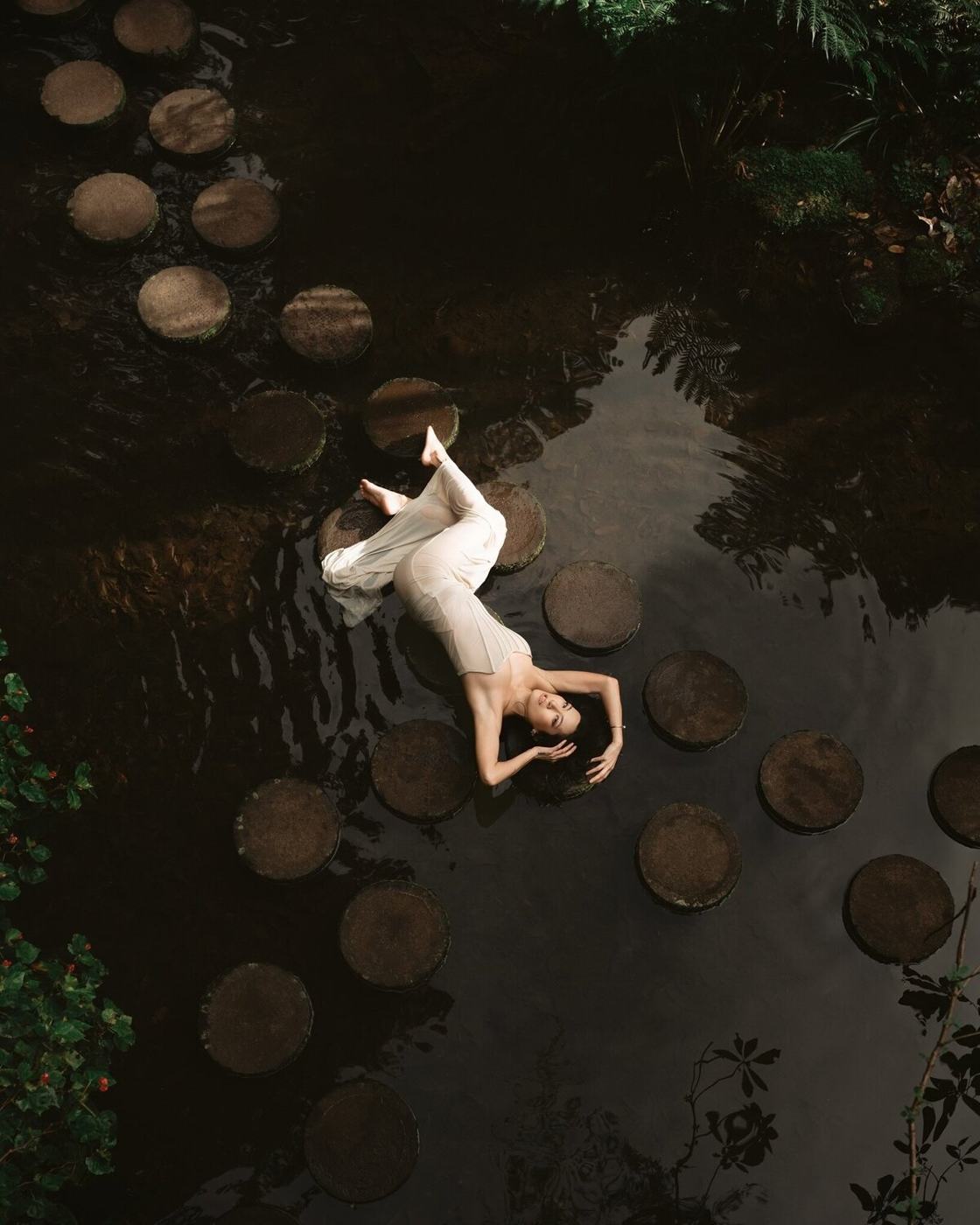 Kristina reclining on stepping stones surrounded by water