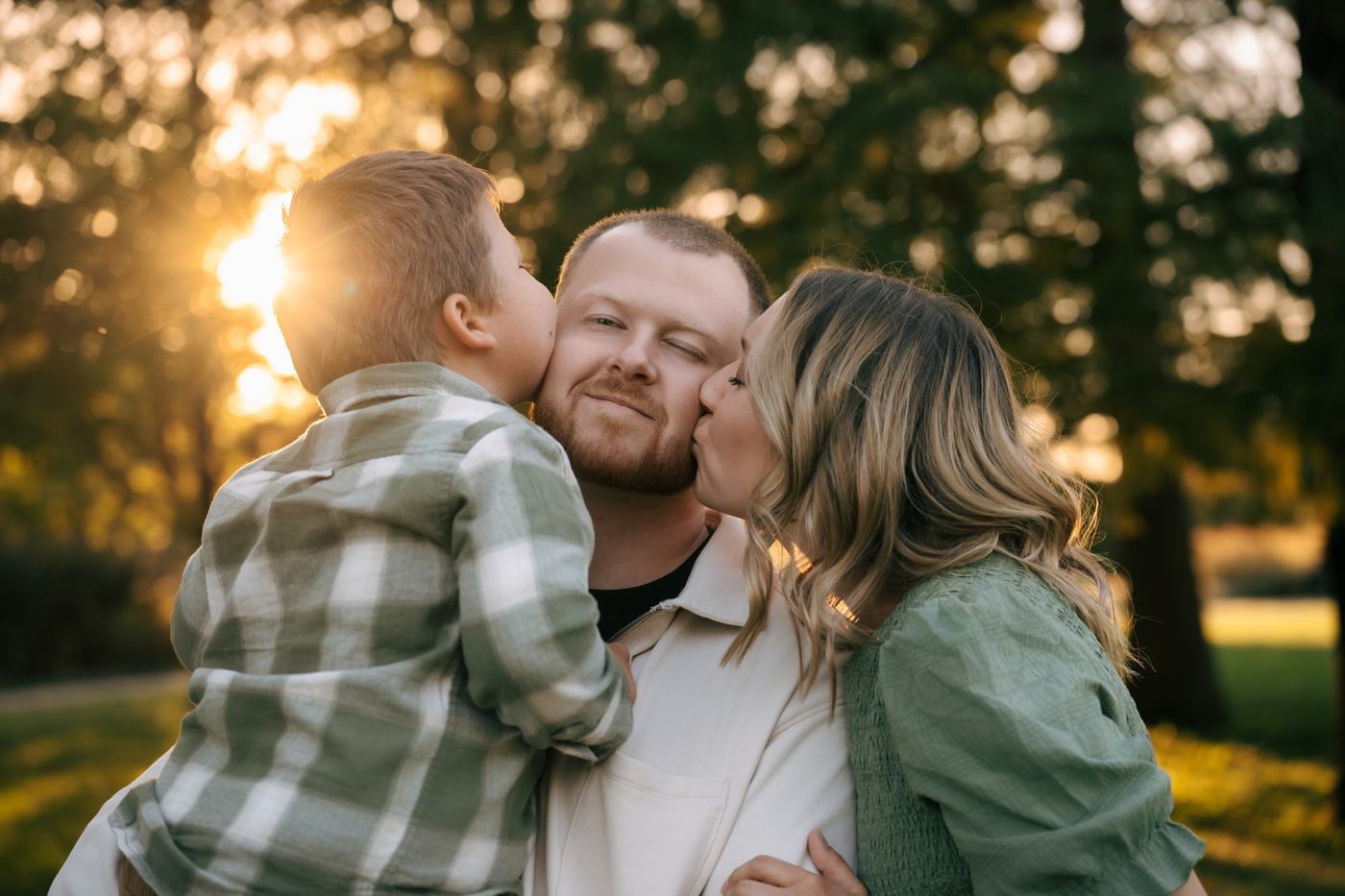 Parents cuddling their child in golden evening light