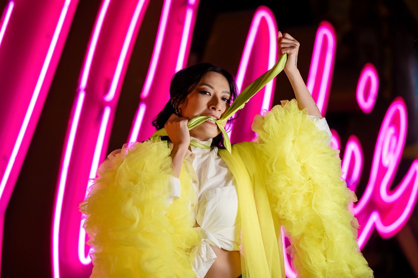 Portrait in yellow feathers surrounded by pink neon lights